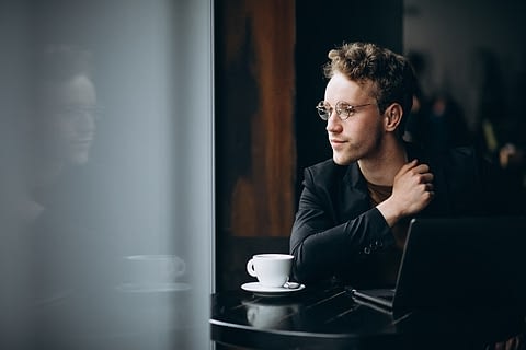 Handsome man working on a computer in a cafe and drinking coffee Handsome man working on a computer in a cafe and drinking coffee